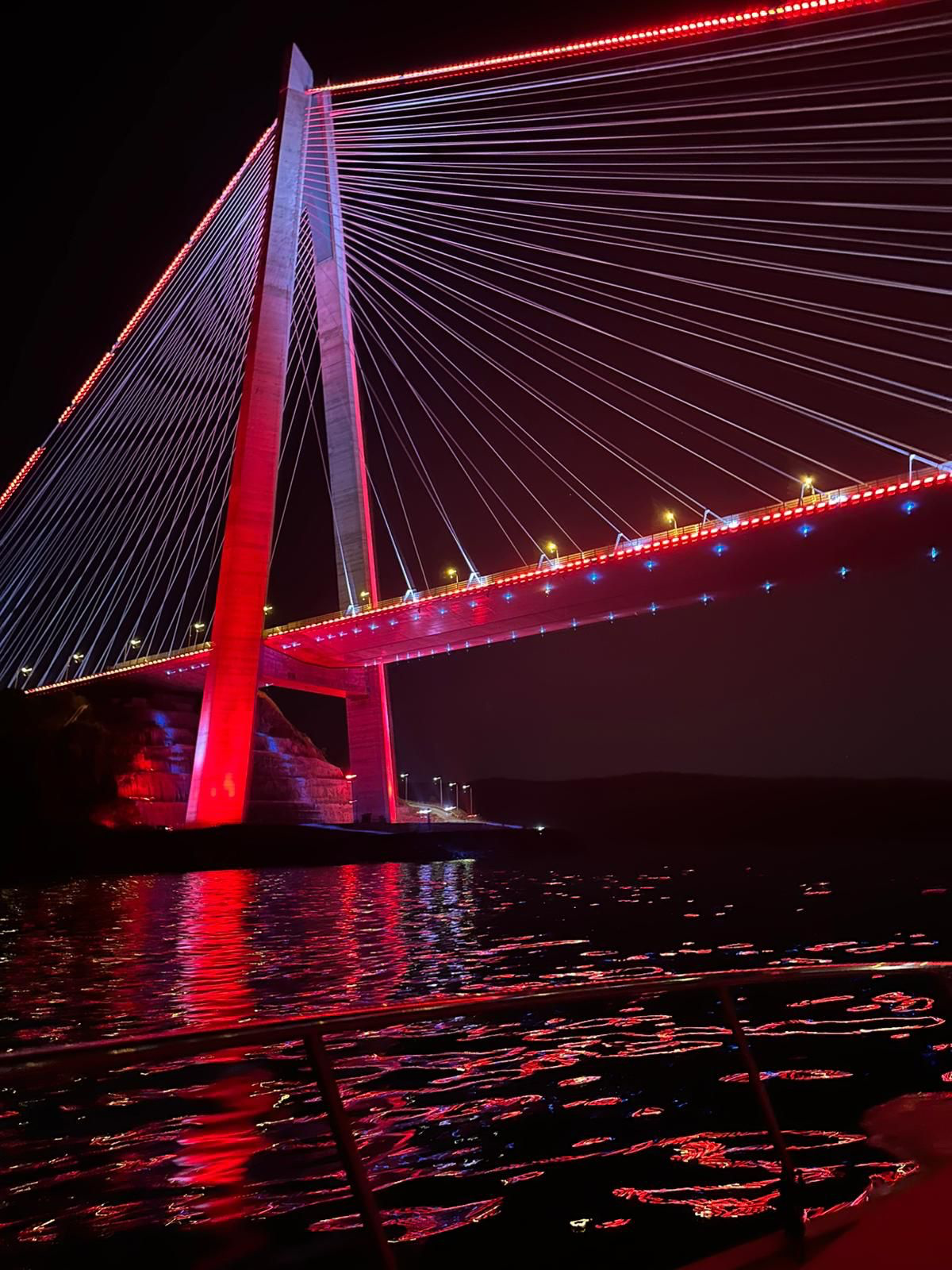 Kırmızı ışıklarla aydınlatılmış köprü ve gece denizi
